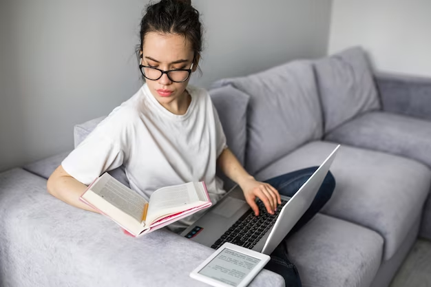 Woman reading book and using laptop