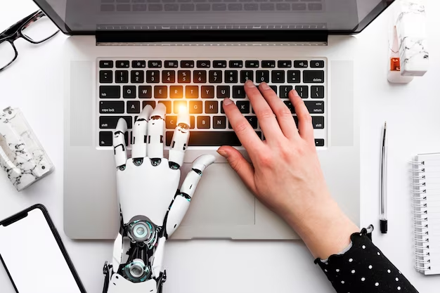 Hand typing on a laptop: one hand is robotic, the other is human.